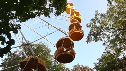 Close-up shot of yellow ferris wheel spinning on sunny day through the foliage Stock Footage 139540825