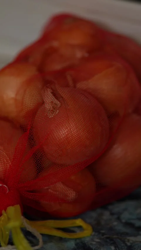 A close-up shot of yellow onions packed in red mesh. Stock Footage 343414487