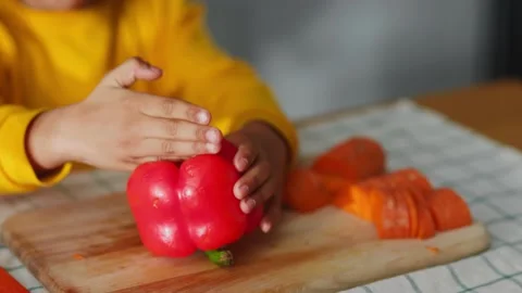 Close-up shot young boy child learning to cut vegetables putting fresh red Stock Footage 147270989