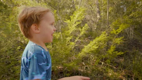 Close up shot of young boy laughing and running on a bush track slow motion Video stock 130226503