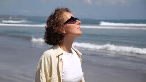 A close shot of a young curly-haired woman throwing her head back and basking in Stock Footage 245495871