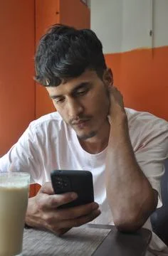 Close-up shot of a young guy using his phone while sitting in cafe Stock-Fotos