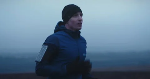 Close up shot of young handsome man in sportswear running fast outdoors on foggy Stock Footage 148332022