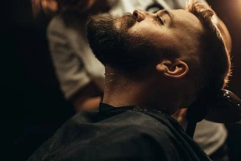 Close shot of a young man beard while he is sitting at a barbershop Stock Photos