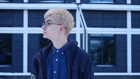 Close up shot of a young man in a glasses looking at the side on the grey Stock Footage 87790136