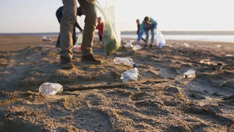 Close up shot of young man picking up plastic bottles on the beach, slow motion Stock Footage 107739823