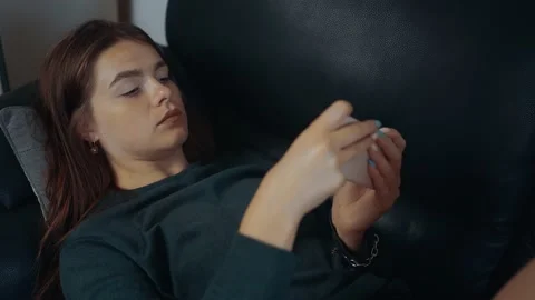 Close-up shot of the young redhead, lying on the couch, playing video games on Stock-Footage 160159782