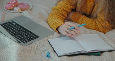 Close-up shot young student something writing in exercise book, when she lying Stock Footage 127249547