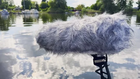 Close-up of a shotgun microphone with a furry windscreen mounted on a boom pole Stock Footage 343901821