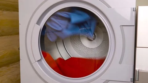 Close-up shots of a spinning dryer drum with blue and red clothes inside. Stock Footage 155924925