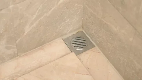 Close-up of Shower Drain on Wet Marble Floor Tiles 動画素材 336563525