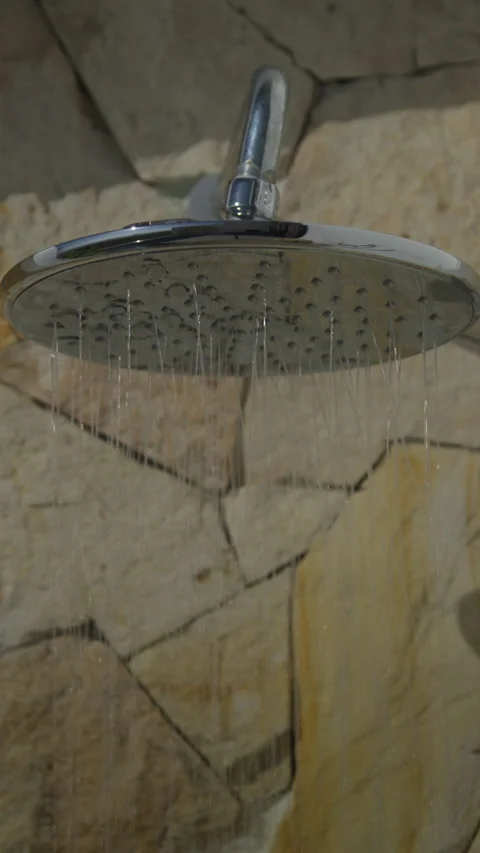 Close up of a shower head spraying water on a natural stone wall Stock Footage 339197714