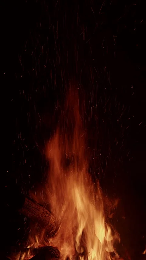 Close-up of a shower of sparks flying from a fire at night. Vertical video. Stock Footage 312609918