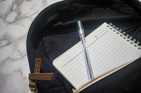 Close up showing a pen and notepad inside a black backpack, ideal for theme.. Foto stock
