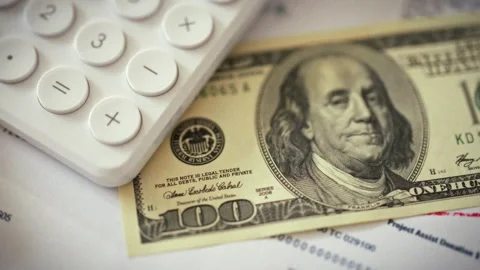 Close-up shows crisp paper one-hundred-dollar bill resting beside white calc Stock Footage 336570734