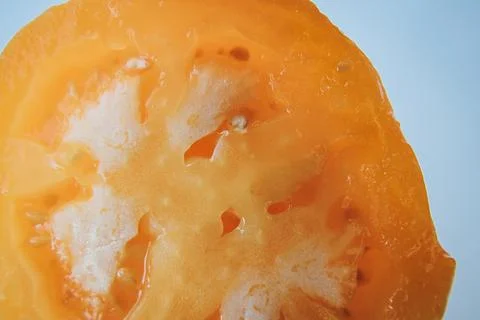 A close-up shows the cross-section of a ripe yellow tomato. Stock Photos