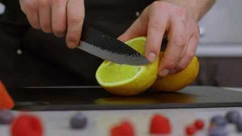 A close-up shows drops of water on a bright orange. The cook skillfully cuts an Vidéo 269123555