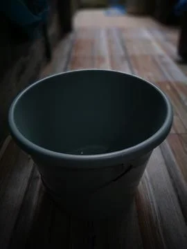 A close-up shows a gray plastic bucket resting against a textured wall, offer Stock Photos