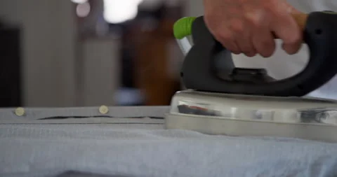 A close-up shows a hand pressing an iron down onto Vidéo 344313149