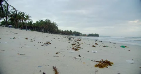 Close-up shows trash and plastic trash bags strewn across the beach. Shoote of Stock Footage 148333197