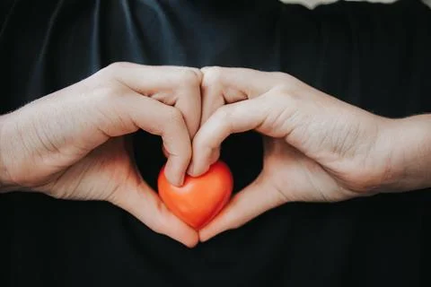 A close-up shows two hands forming a heart shape. Stock Photos