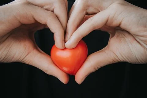 A close-up shows two hands forming a heart shape. Stock Photos