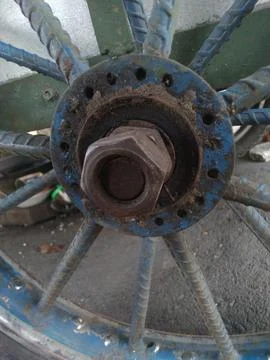 A close-up shows a wheel hub with a large nut, blue metal spokes Fotos Stock
