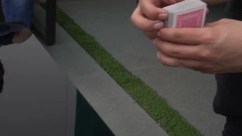Close-up shuffling playing cards with hands on glass table at daytime in 4k Видео 155811970