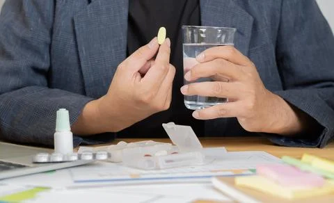 Close up of sick man worker feel unhealthy take pill medications with a gla.. Stock Photos