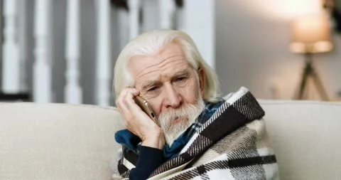 Close up of sick sad grey-haired man sitting on sofa at home and speaking on Stock Footage 141324100