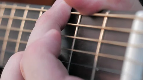 Close-up side angle shot of fingers playing a guitar. Musician clamps the chords Stock Footage 113535449