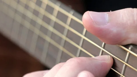 Close-up side angle shot of fingers playing a guitar. Musician clamps the chords Stock Footage 113538254