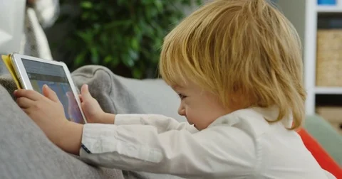 Close up from the side of the cute lovely small boy playing games on his tablet Stock Footage 82916132