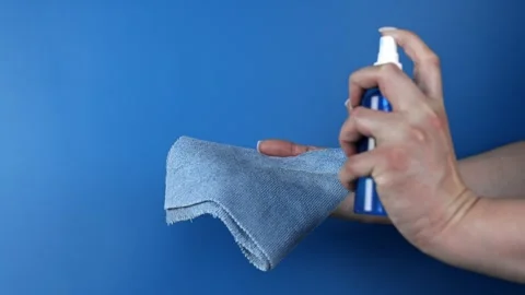 Close-up, at the side, a hand holds a cleaning cloth and a jar of aerosol and Stock Footage 307169671