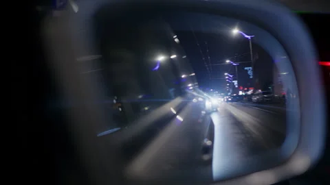 Close up of a side mirror at night with bright headlights from a car behind Stock Footage 329396640