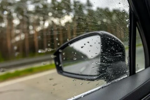 Close side mirror with raindrops. Rainy car window detail. Stock Photos