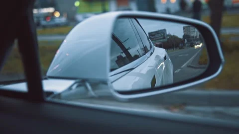 Close-up side mirror rear view of white modern beautiful car driving on city Stock Footage 148981274