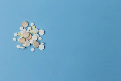 Close up of a side placed pile of various tablets lay down a light blue surface 스톡 사진