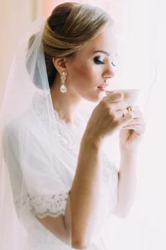 Close-up side portrait of the bride drinking tea near the window. Stock Photos