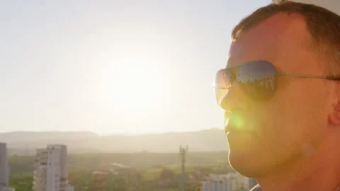 Close Up Side Portrait of Man in Sunglasses at Sunset with City and Mountains 스톡 동영상 330780202