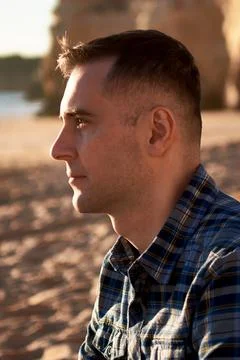 Close-up side profile of a man in a blue plaid shirt on a beach Stock Photos