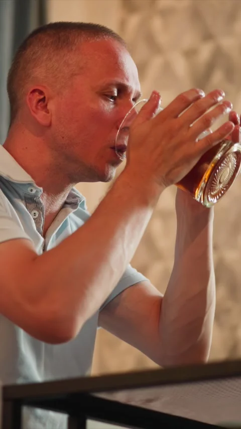 Close up side profile of man lifting sipping from glass with soft lighting Stock Footage 344796924