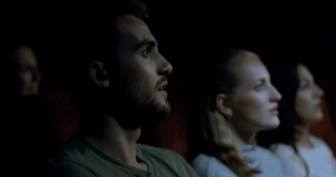 Close up, side on shot of a movie theatre audience watching a film Stock Footage 95616530