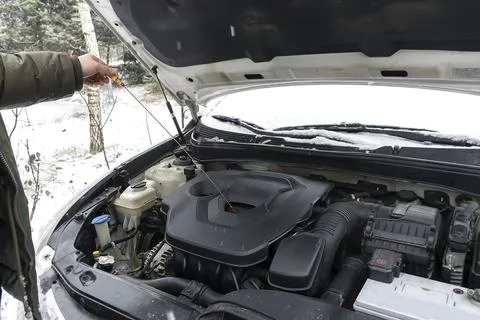 Close-up side view of auto mechanic man checking engine oil level in car, wor Stock Photos