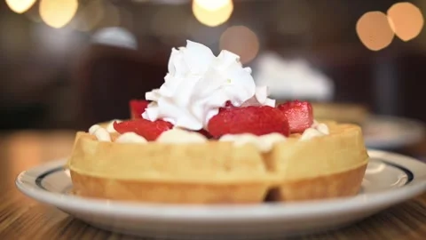 Close-up side view Belgian waffles with cream and strawberries on breakfast. Stock Footage 268952594