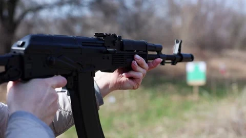 Close-up side view of a black air gun held by a woman and aiming at a target Stock Footage 307169532