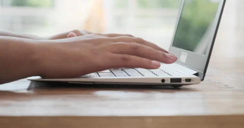 Close-up side view of a black lady typing on a laptop keyboard while working Stock Footage 157970043