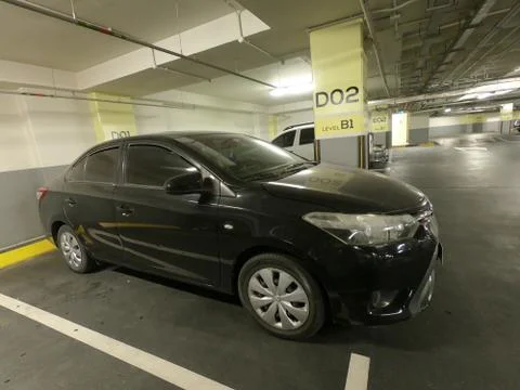 A close-up of side view of a dirty black car in a basement parking lot. Stock Photos
