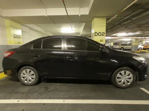 A close-up of side view of a dirty black car in a basement parking lot. Stock Photos
