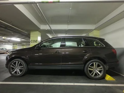 A close-up of side view of a dirty brown suv car in a basement parking lot. Stock Photos